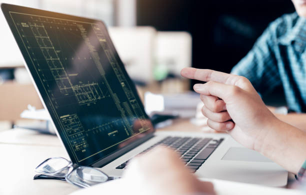 Teenagers develop programming with blueprint code in laptop monitor.